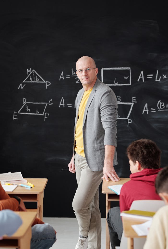 Male teacher explains geometry to students in classroom.